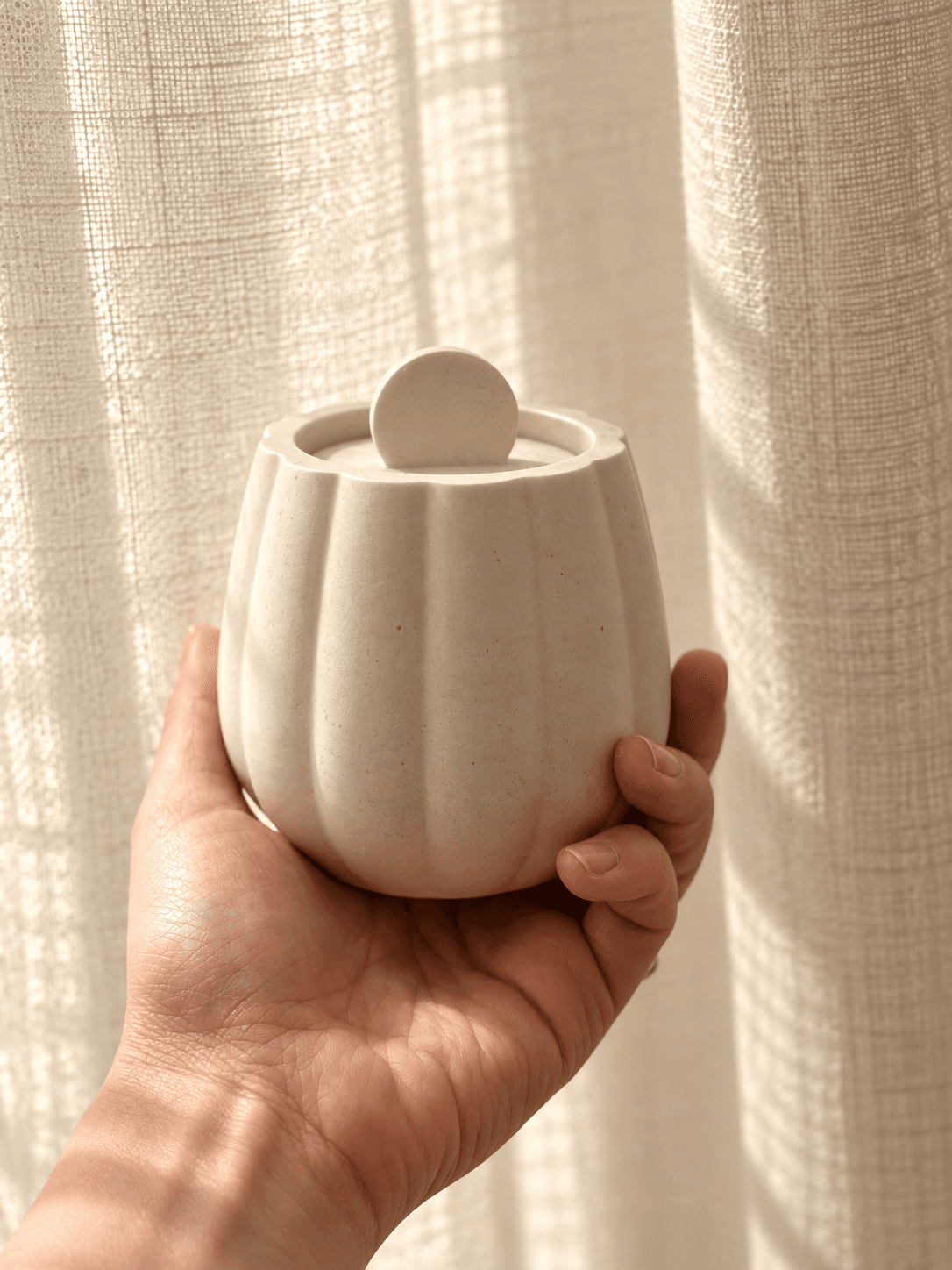 Fluted lidded jar held in the hand